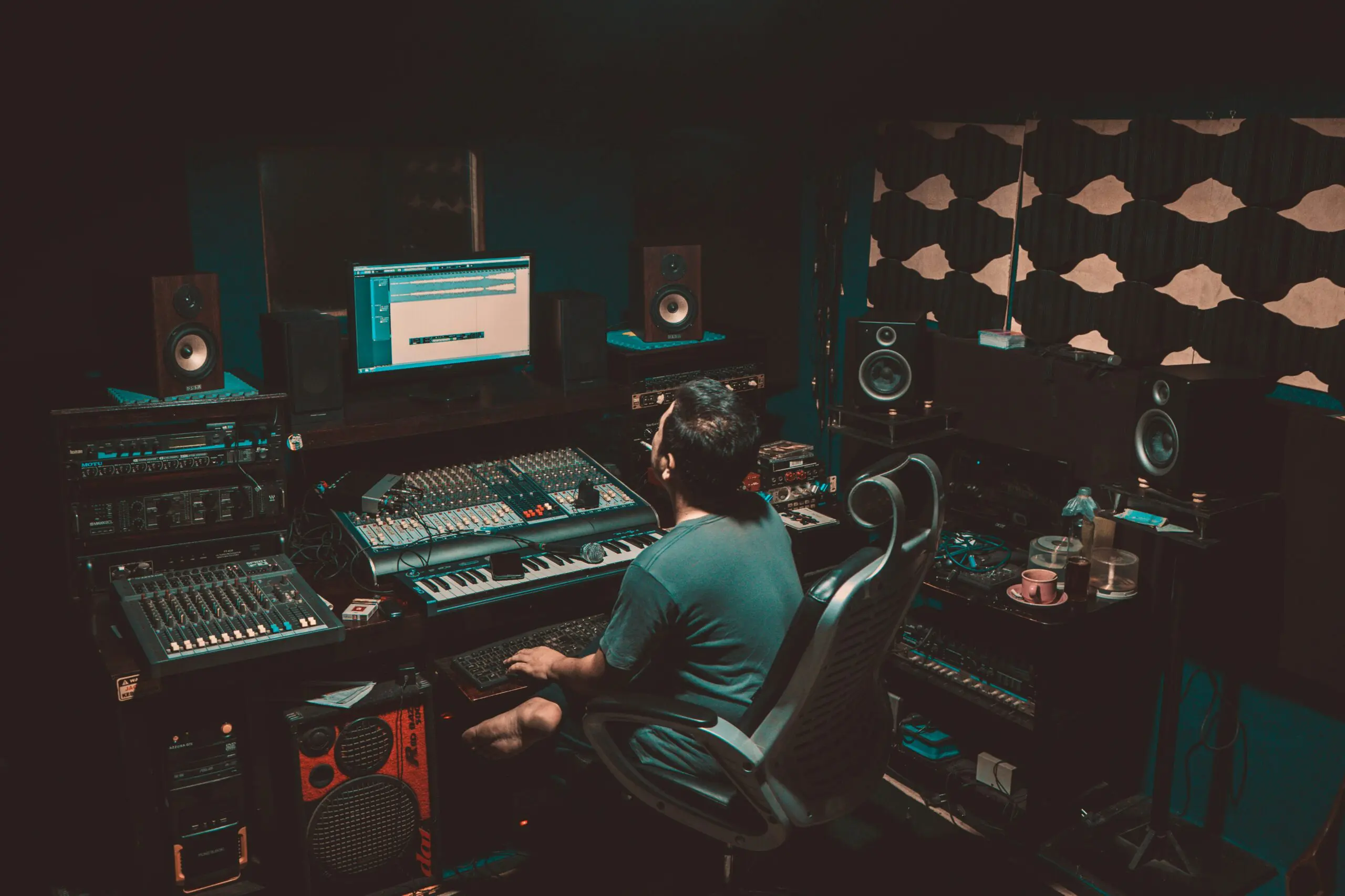 An engineer sitting at his workstation in a recording studio. Photo courtesy of Jesman Fabio via Unsplash