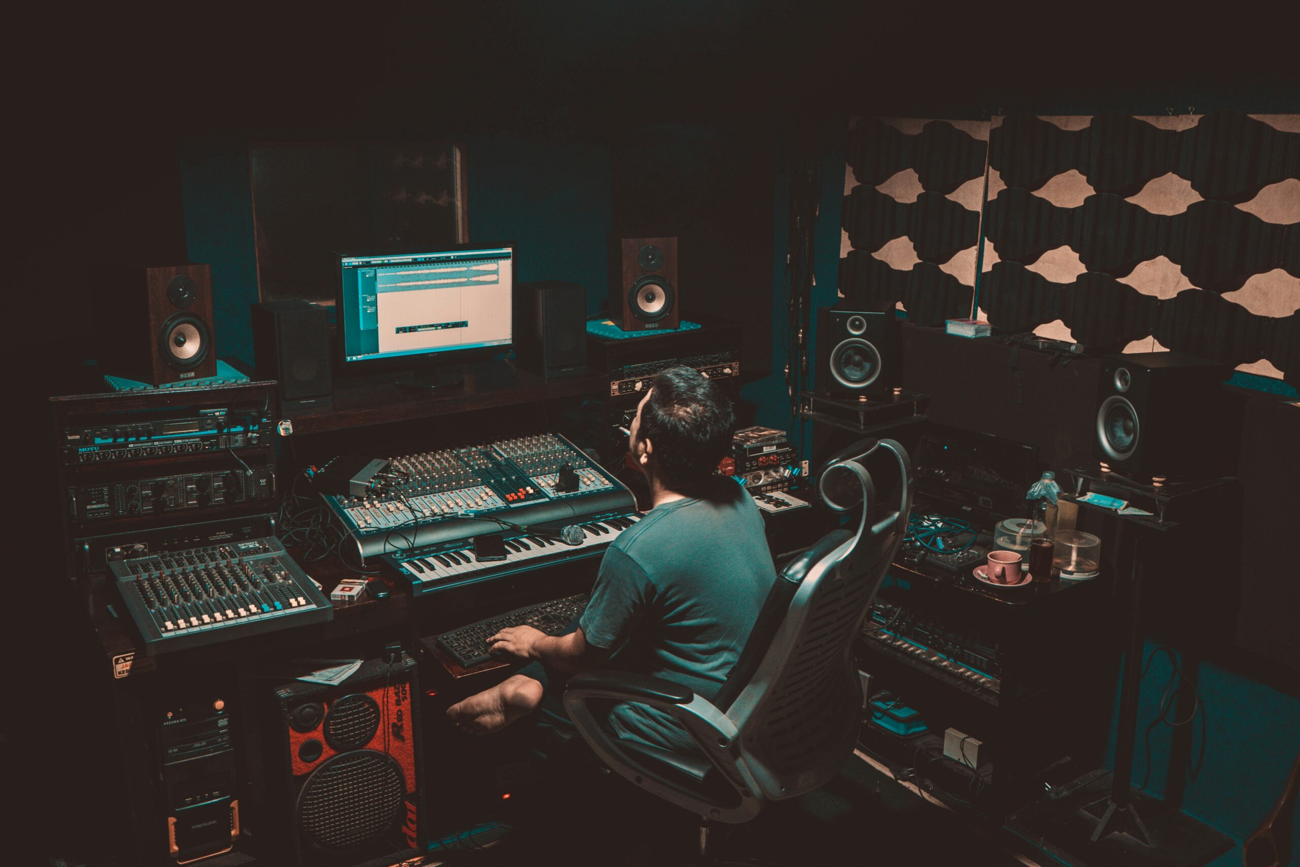 An engineer sitting at his workstation in a recording studio. Photo courtesy of Jesman Fabio via Unsplash